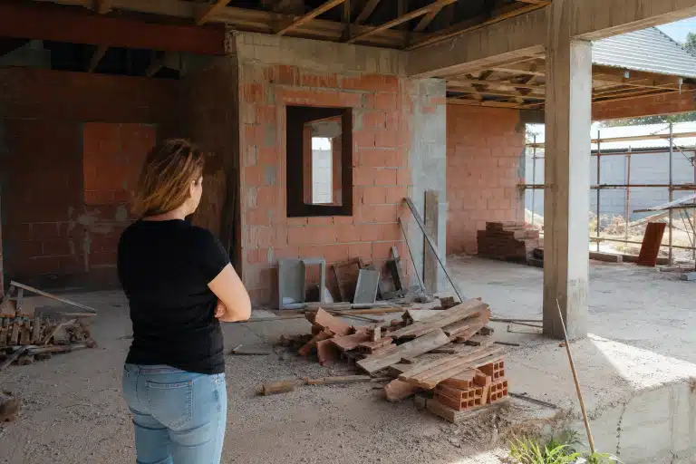 Femme bras croisés observant intérieur de chantier inachevé